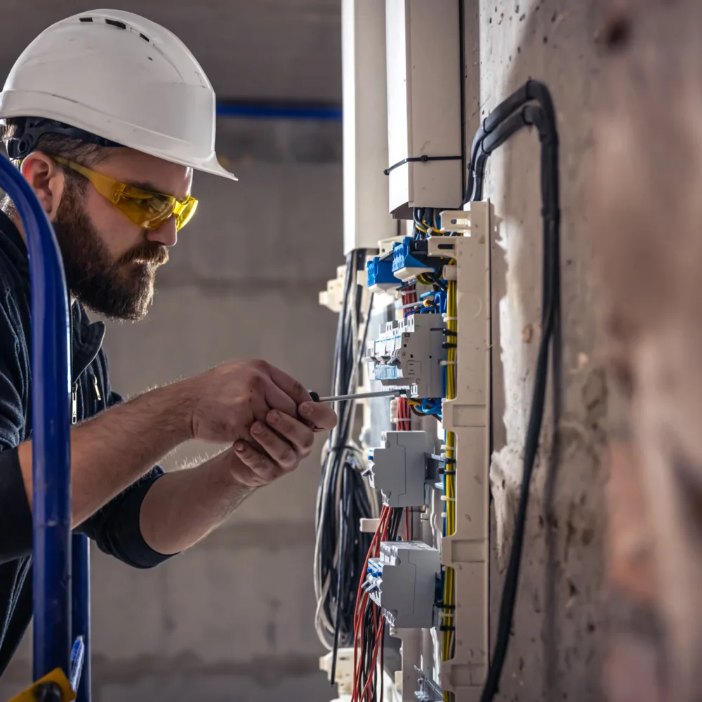 male-electrician-works-switchboard-with-electrical-connecting-cable